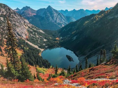 Round lake in valley between mountain with bright fall colors